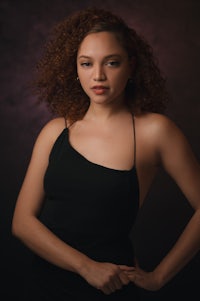 a young woman in a black dress posing for a portrait