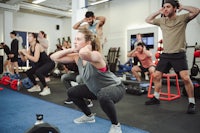 a group of people doing squats in a gym