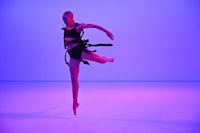 a dancer in a black outfit is jumping in the air