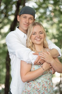 a man and woman hugging in the woods