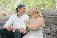 a couple sits on a log in the woods during their engagement session
