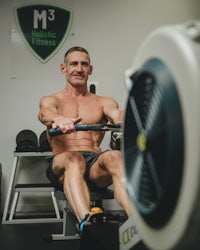 a man sitting on a rowing machine in a gym
